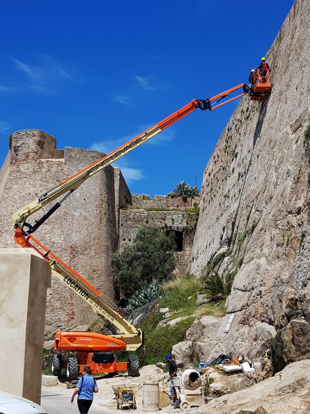 A plusieurs mètres du sol, les ouvriers s'affairent à la rénovation des remparts de la citadelle de Calvi