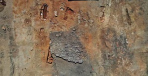 Empierrement en partie fouillé sous lequel apparaît la tombe en bâtière décorée. Photo Inrap. Empierrement en partie fouillé sous lequel apparaît la tombe en bâtière décorée. Photo Inrap.