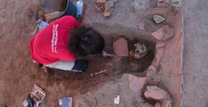 Une archéologue de l’Inrap est en train de fouiller une sépulture médiévale en pleine terre ayant recoupée une sépulture en amphore africaine antérieure. Photo Inrap.