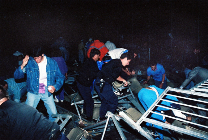 Au milieu des débris métalliques et des corps brisés, secours et spectateurs tentent de sauver les milliers de personnes tombées avec la tribune. Archive : Gérard Baldocchi