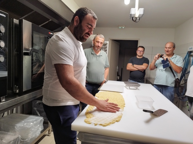 Le député Paul-André Colombani observe le savoir-faire artisanal de François-Marie Scelo dans la fabrication des canistrelli.