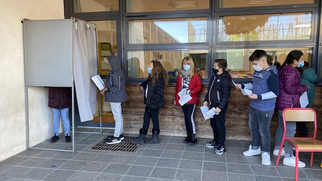 Les enfants enthousiastes se bousculaient vers l'isoloir