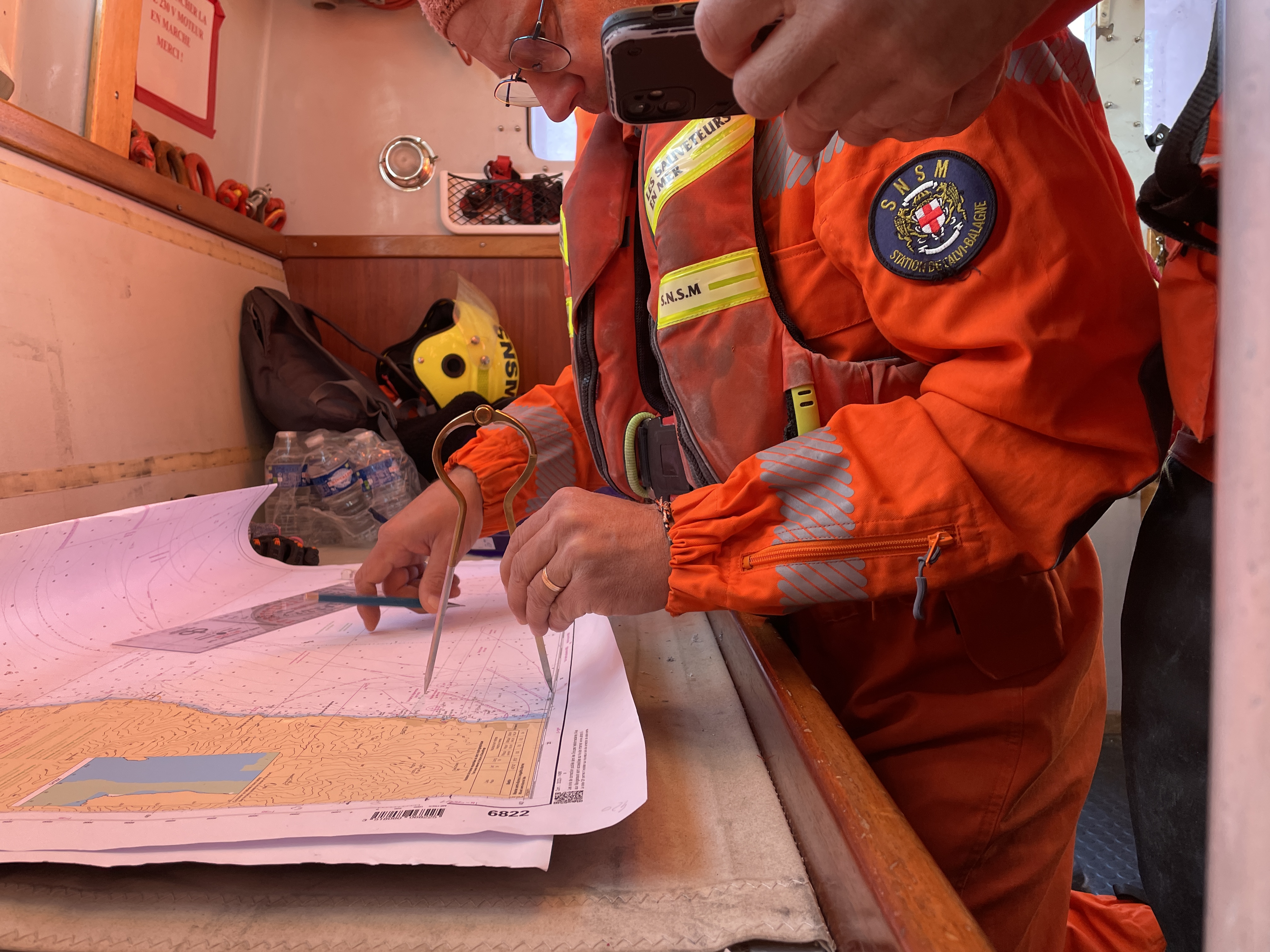 Les sauveteurs prennent les mesures de leur destination sur une carte, à l'aide d'une règle et d'un compas. Crédit photo: David Ravier.