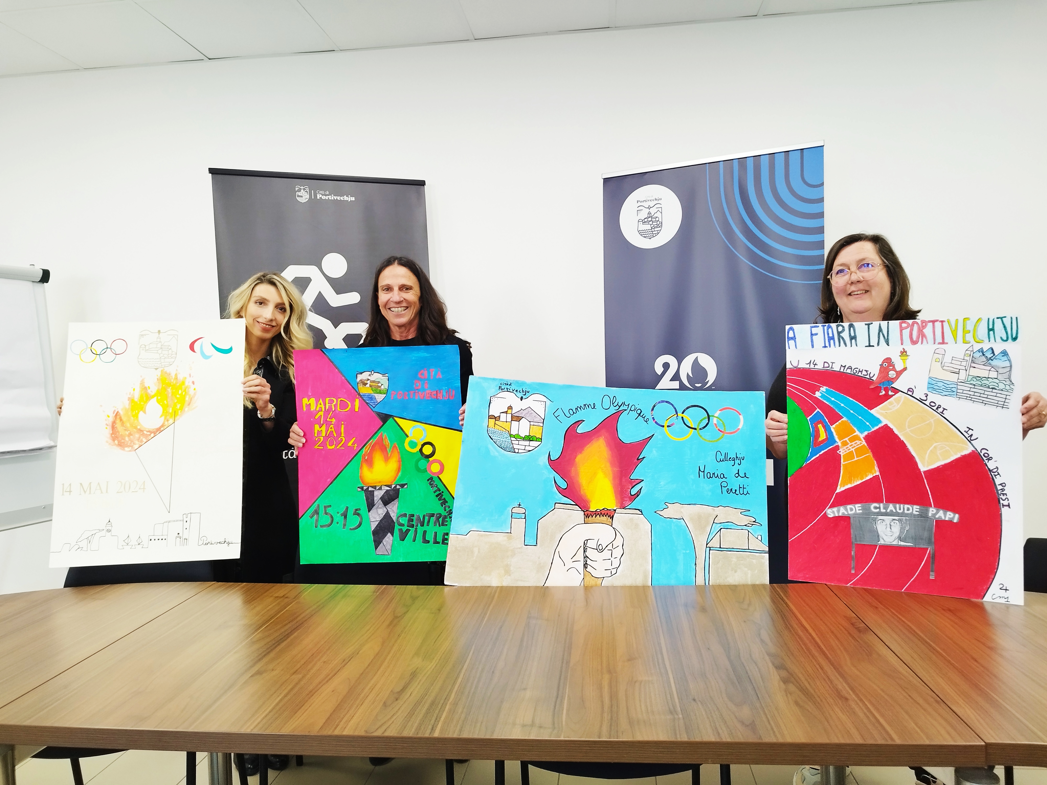 Serena Gatta (directrice jeunesse et sport), Véronique Filippi (adjointe aux sports) et Nathalie Maisetti (déléguée aux affaires scolaires) posent devant les affiches lauréates du concours organisé dans les écoles de Portivechju.