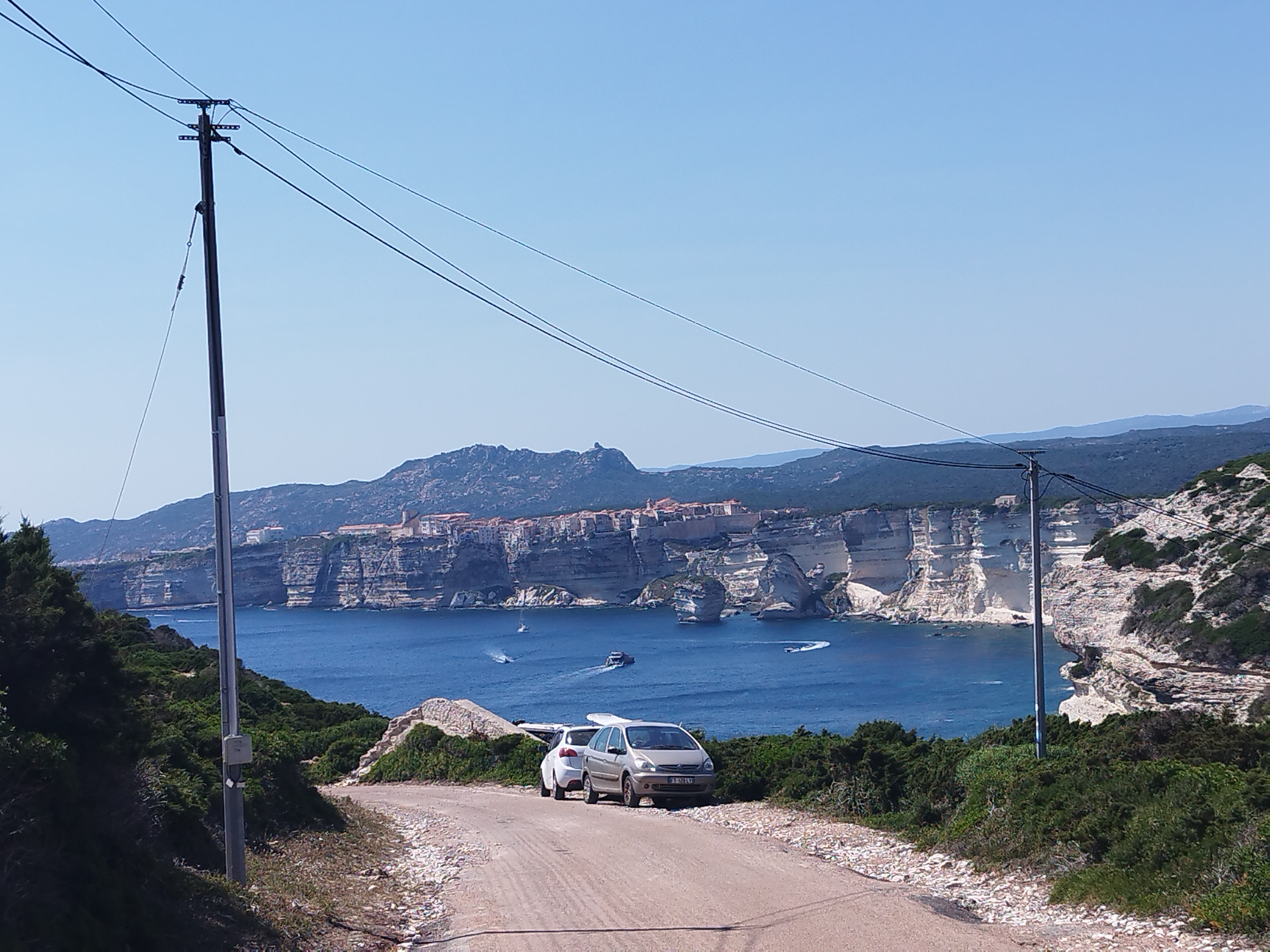 Stationnement sauvage et réseaux électriques représentent une pollution visuelle sur la route d'accès au site.